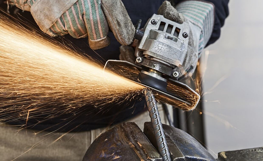 Person wearing protective gloves using grinding wheel on aluminum bar