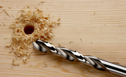 Freshly drilled saw hole with drill bit beside