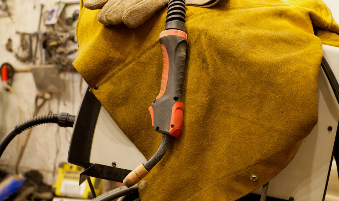 Leather welding jacket and gloves with welding torch draped overtop
