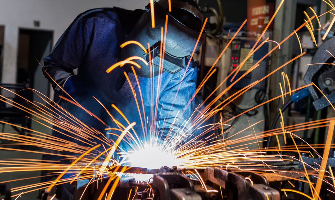 Welder in safety equipment welding car parts in factory