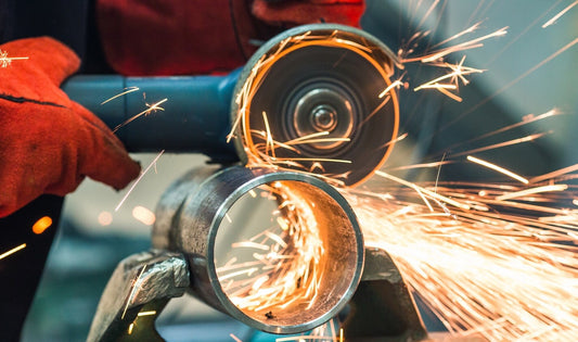Welder using grinding wheel on metal pipe with sparks flying