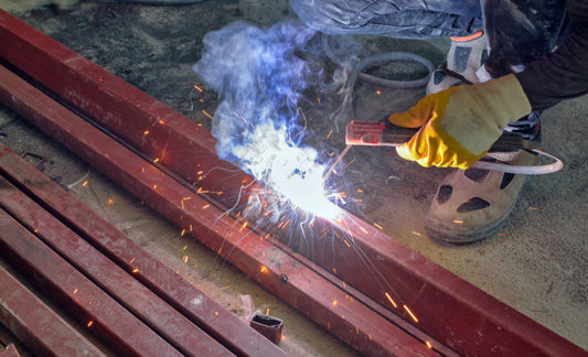 Welder wearing PPE working with steel pipe with sparks flying