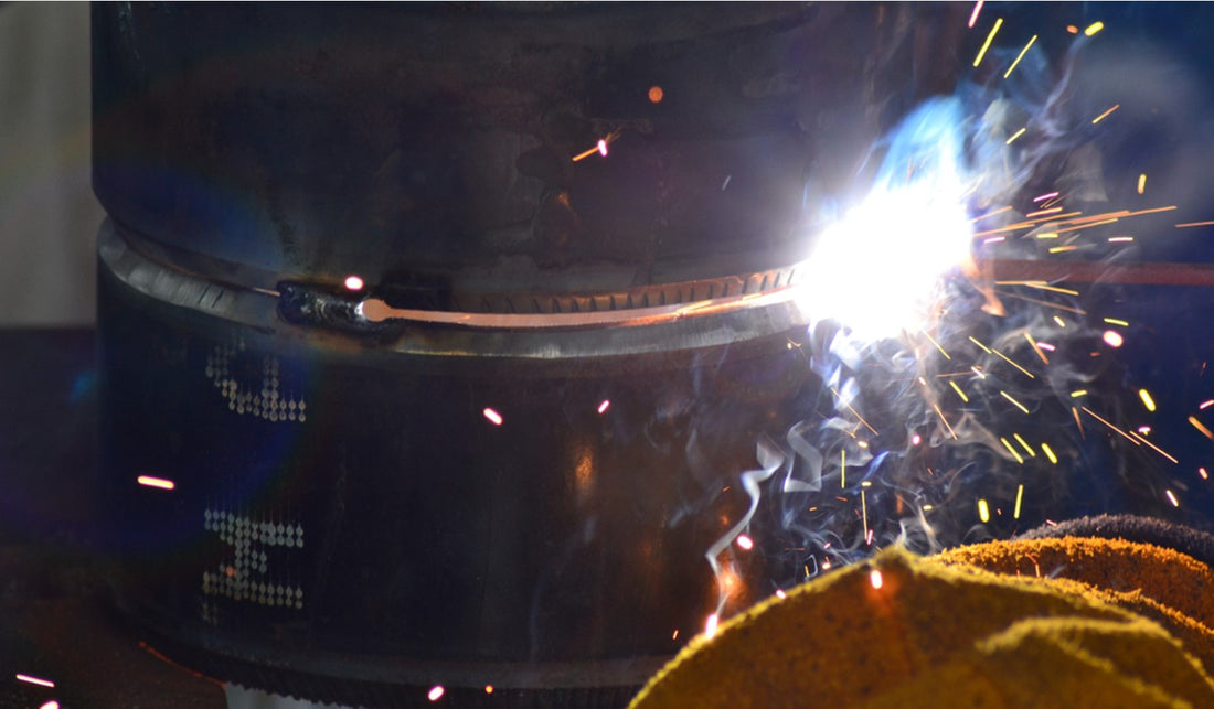 Welding large metal pipe with sparks and smoke