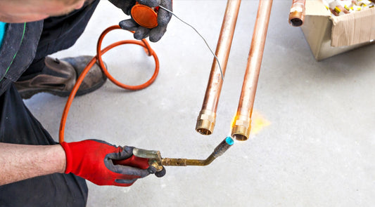 plumber brazing two copper pipes with blow torch